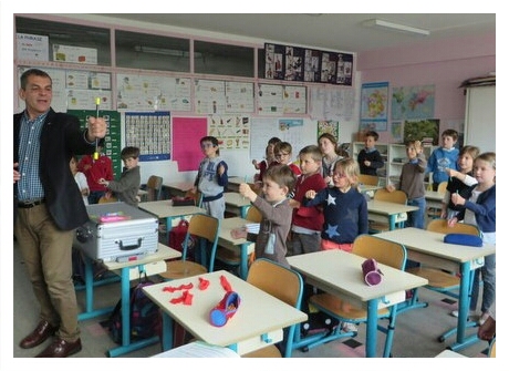 Le magicien montre à la classe comment faire tenir par magie un crayon ou une baguette dans sa main.